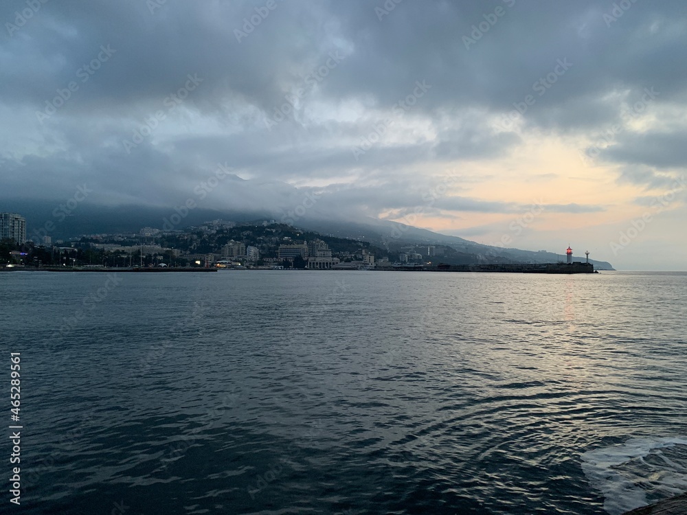 view of the city of Yalta from the sea in the predawn hour, cloudy sky