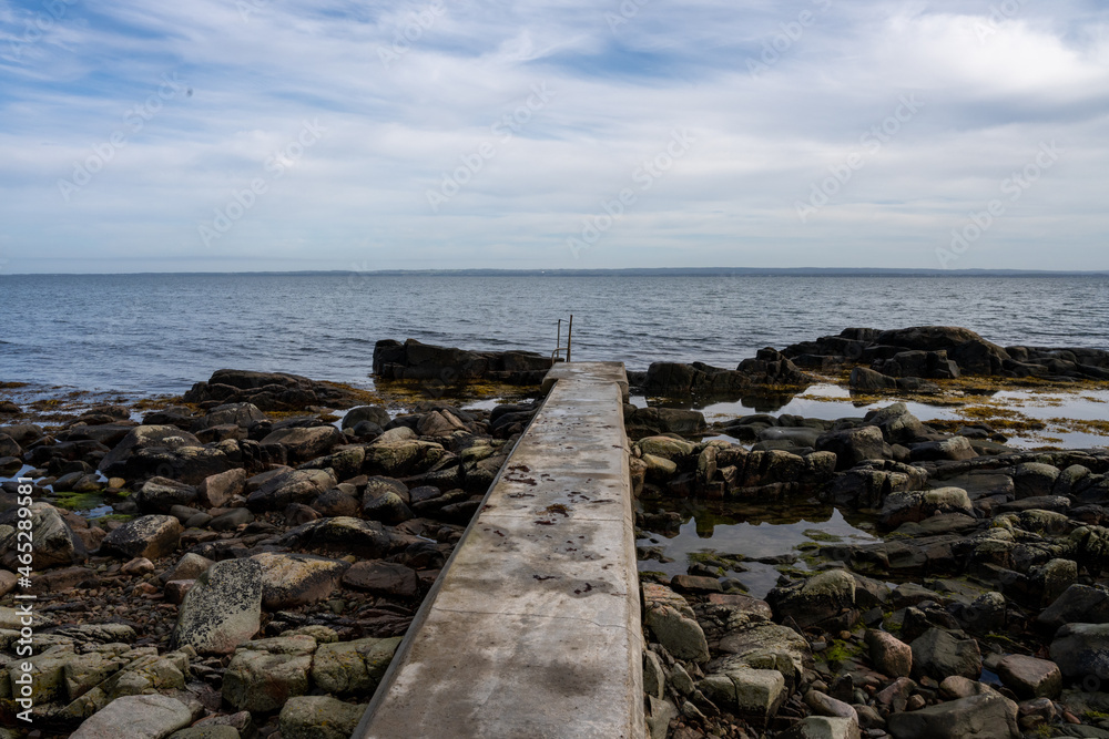 Rocky shoreline with a concrete jetty. Blue water and a blu sky in the background. Picture from Skalderviken, southern Sweden