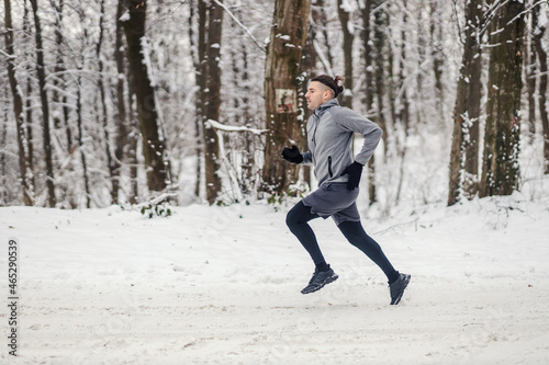 Fast sportsman sprinting in nature at snowy winter day. Winter fitness, cardio exercises, cold weather