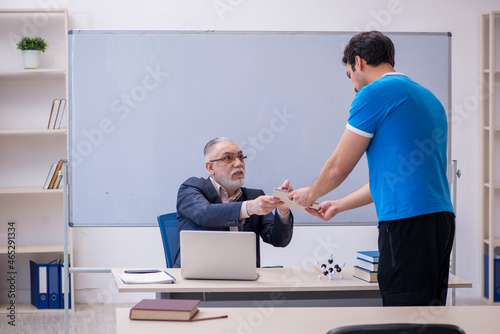 Old male teacher and young male student in front of whiteboard