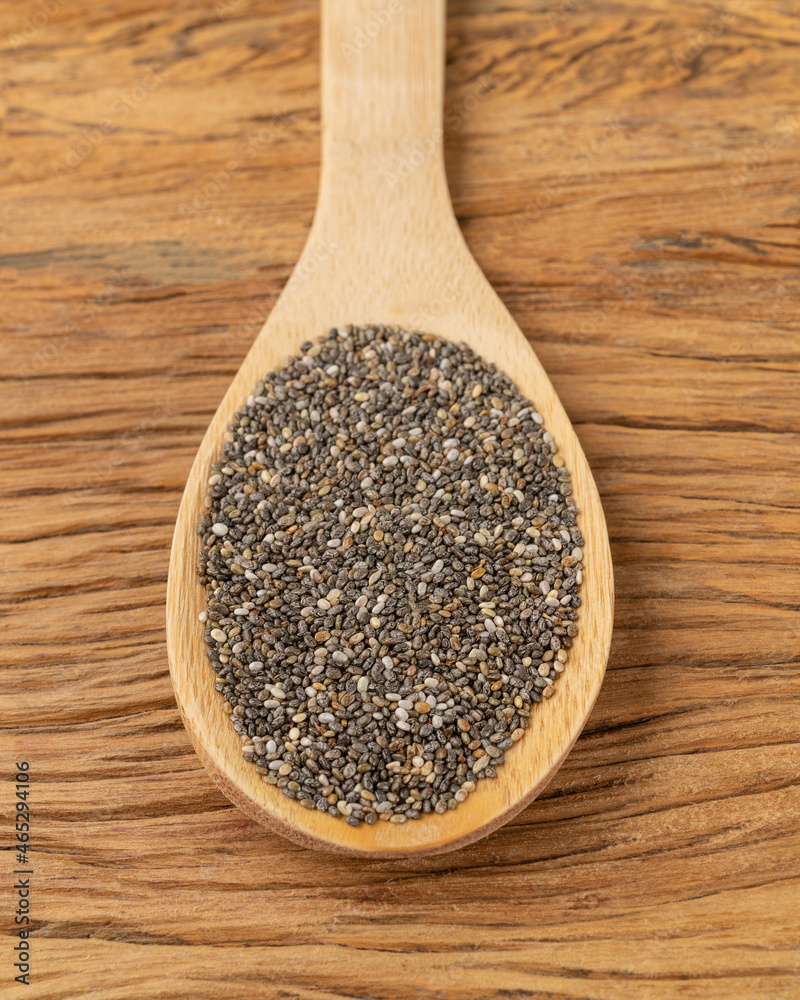 Chia seeds in a spoon over wooden table Chia seeds in a spoon over wooden table