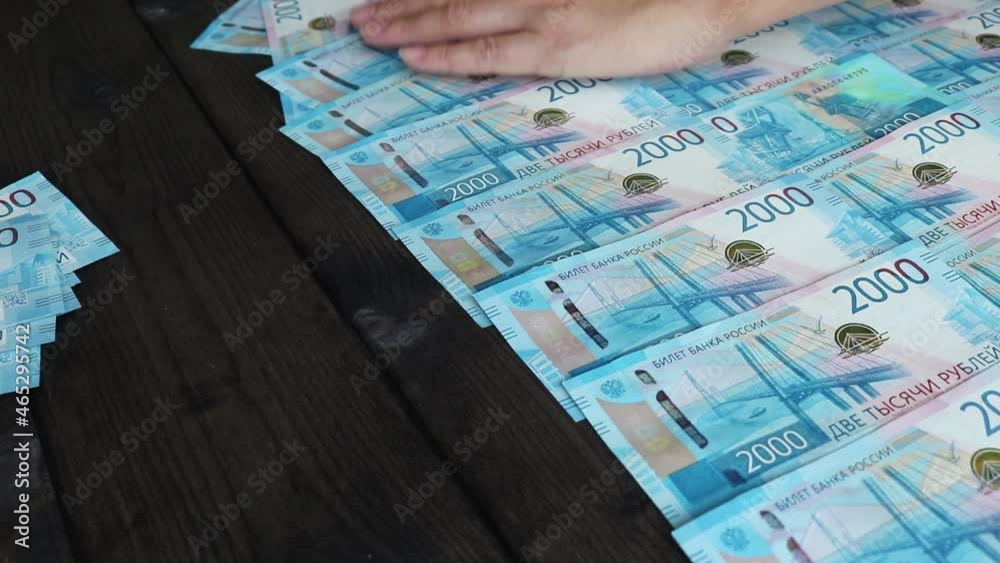 Hands are clearing 2,000-ruble Russian bills from the table. Money background. Hands are clearing 2,000-ruble Russian bills from the table. Money background.
