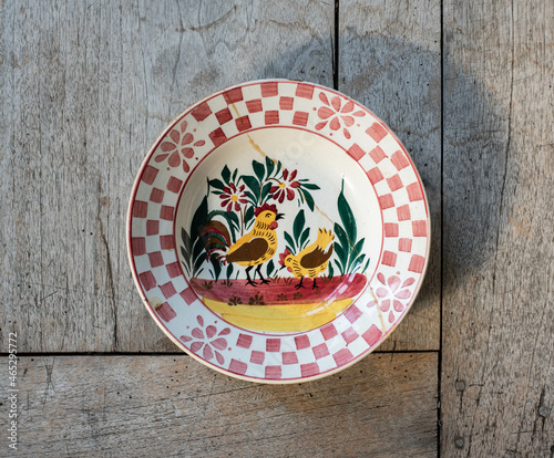 Vintage porcelain plate with chicken and rooster pattern - on a rustic wooden table