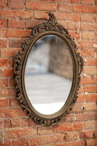 Obraz na płótnie A mirror in a vintage openwork frame hangs on an old brick wall