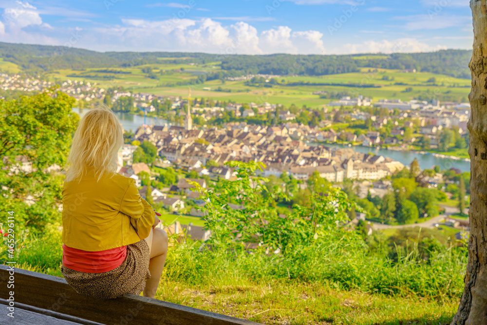 Girl looking cityscape of Stein am Rhein and its terraced vineyards in Switzerland. Lookout of terraced vineyards with an aerial view of skyline on the River Rhine. Swiss canton Schaffhausen.