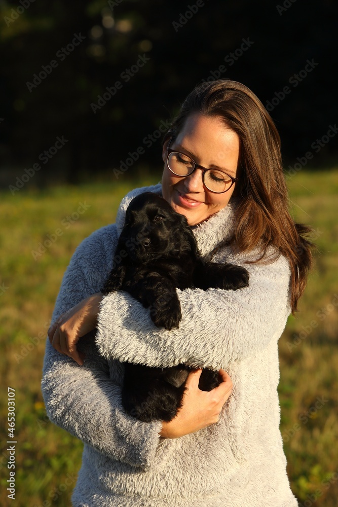 Small and cute black Cocker Spaniel puppy in the human hug, morning sun. Small and cute black Cocker Spaniel puppy in the human hug, morning sun.