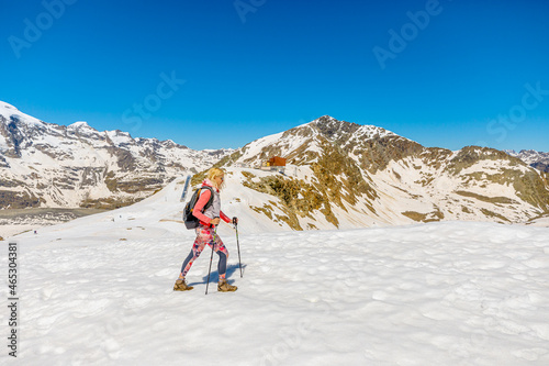 Woman walking with trekking poles on top of Diavolezza col between Munt Pers and Piz Trovat of Switzerland. Piz Bernina skyline view with Morteratsch glacier in Graubunden canton in Switzerland.