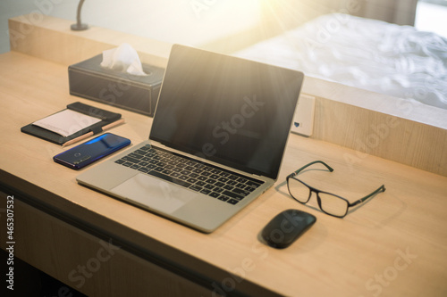 Side view of laptop computer, notebook, coffee cup and stationery on wooden table.