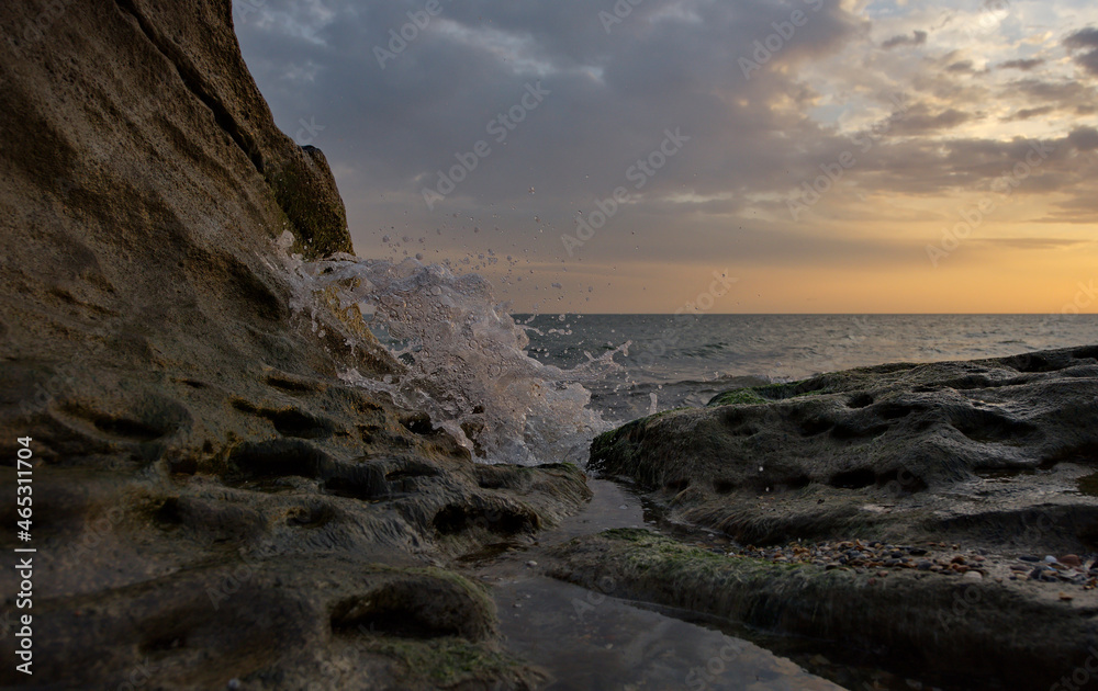 Russia. Republic of Dagestan. Sea surf splashes on the coastal rocks of the Caspian Sea against the background of the dawn sky on the embankment of the city of Makhachkala.