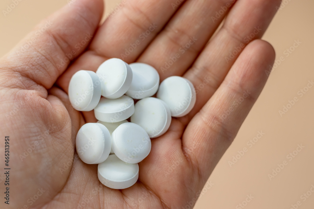 round white tablets poured chaotic light orange background,heart shape.pills in woman hand or green spoon.natural herbs,organic pills,vitamins from medicinal plants,calcium, antidepressants,painkiller round white tablets poured chaotic light orange background,heart shape.pills in woman hand or green spoon.natural herbs,organic pills,vitamins from medicinal plants,calcium, antidepressants,painkiller