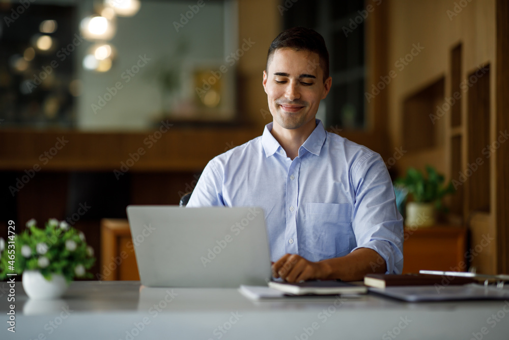 Smiling businessman working on a laptop computer in a modern office,doing finances, accounting analysis, report data pointing graph Freelance education and technology concept. Smiling businessman working on a laptop computer in a modern office,doing finances, accounting analysis, report data pointing graph Freelance education and technology concept.