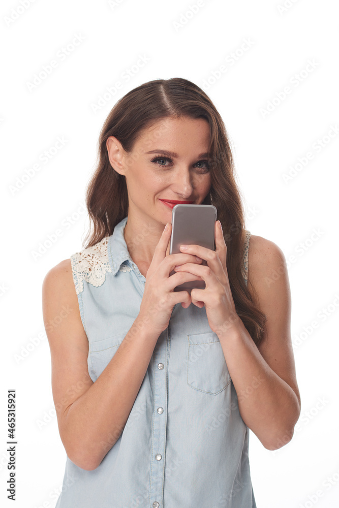Portrait of content pretty young woman in sleeveless shirt holding gadget near face, isolated background Portrait of content pretty young woman in sleeveless shirt holding gadget near face, isolated background