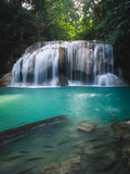 Scenic view of famous Erawan Waterfall. Breathtaking smooth flowing water stream with turquoise lagoon and fish in lush rainforest. Kanchanaburi, Thailand. Long exposure.