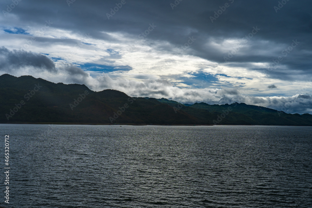 A lake surrounded by mountains There are many tourists' raft boats in the dam of Thailand on a rainy and cloudy day.