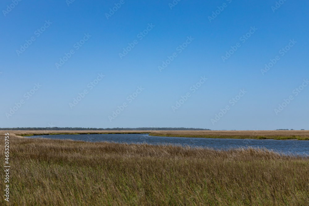 Intracoastal waterway bordered on both sides by salt marsh grasses, brilliant blue sky, horizontal aspect Intracoastal waterway bordered on both sides by salt marsh grasses, brilliant blue sky, horizontal aspect