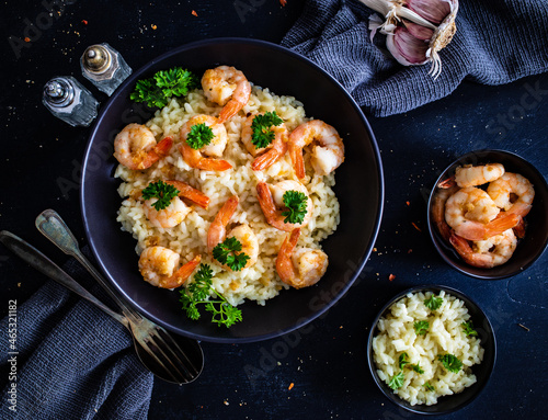 Risotto with prawns, chili and parsley on wooden table