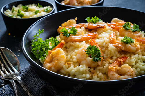 Risotto with prawns, chili and parsley on wooden table

 photo