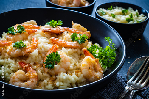 Risotto with prawns, chili and parsley on wooden table


