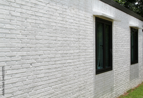 Two black windows on white brick wall.