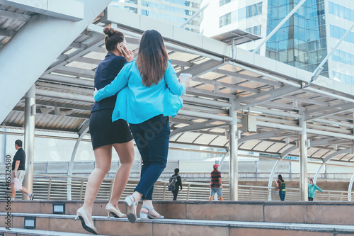 Two business women walking in city for going to work with cityscape background.