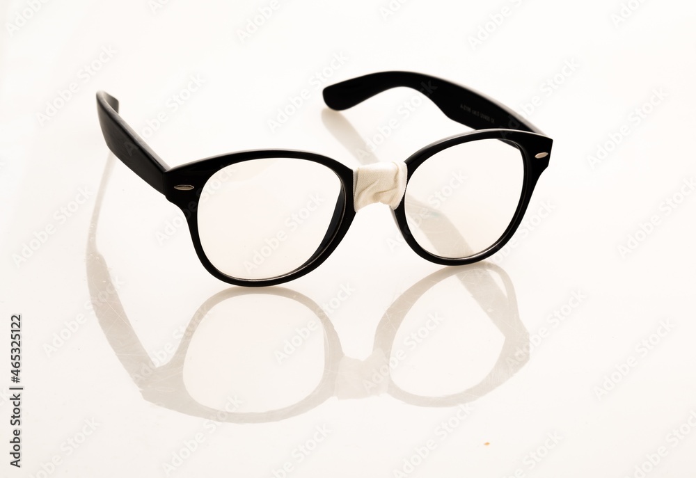 Eyeglasses With Broken Bridge And Its Reflection Against Light Background Eyeglasses With Broken Bridge And Its Reflection Against Light Background