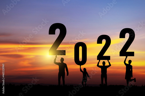 Silhouette people holding numbers 2022 with colorful dramatic sky at sunset. Concept for success in the future goal and passing time