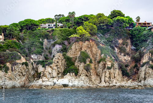 Beautiful wild rocks with coniferous trees on Mediterranean coast in Tossa de Mar located in popular Costa Brava, Catalonia, Spain. Amazing rock cliff seascape in the coastline.