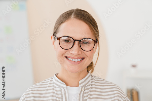 Closeup cropped portrait of caucasian smiling young woman freelancer teacher student wearing glasses with toothy smile looking at the camera.