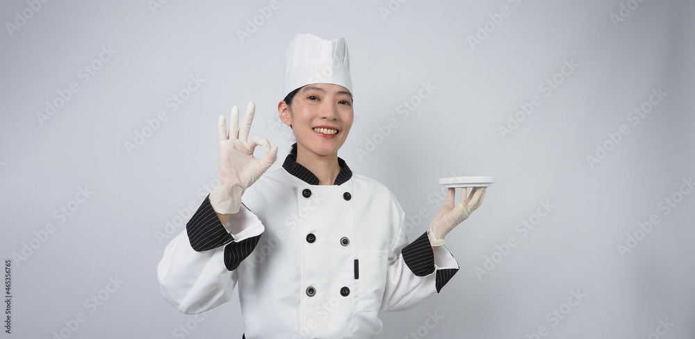 Asian woman chef holding smartphone or digital tablet and received order from online shop or merchant application. she smiling in chef uniform and standing in white background. Online food merchant. Asian woman chef holding smartphone or digital tablet and received order from online shop or merchant application. she smiling in chef uniform and standing in white background. Online food merchant.