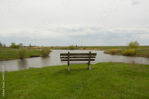 Wooden bench on the shore of the lake for tourists to rest. A weekend getaway for all families. © Maksim