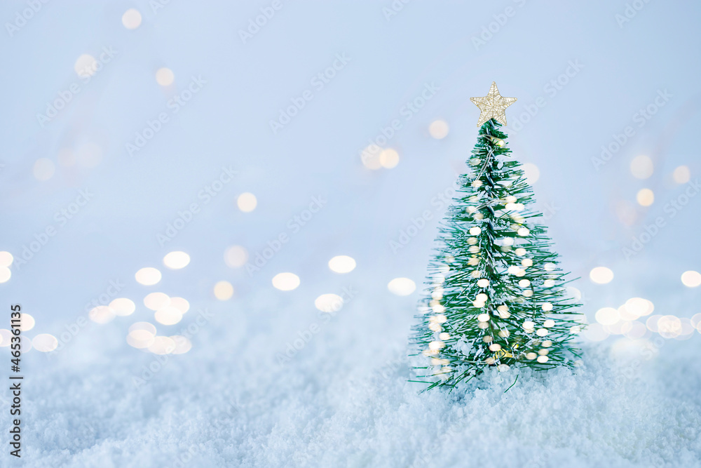 Christmas tree with christmas lights on white snow against bokeh background