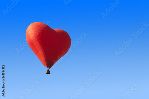 Red heart shaped balloon on blue background