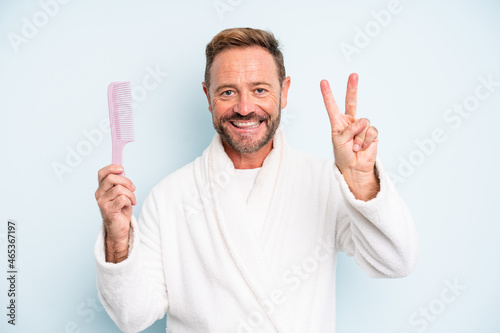 middle age man smiling and looking friendly, showing number two. hair comb concept photo