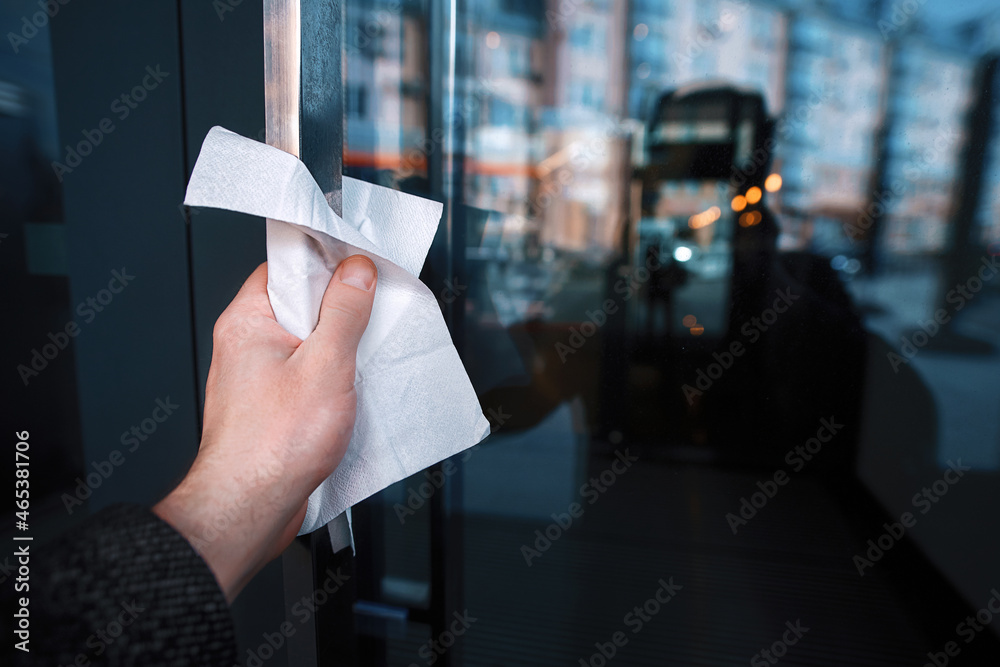 Man use paper towels to open the door. Person do not touch door handle