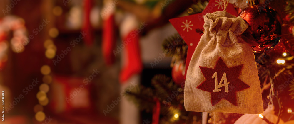 Christmas background. Advent calendar. Advent calendar in the form of an eco bag hangs on the Christmas tree against the background of the Christmas room with a fireplace and Santa's boots.. Banner
