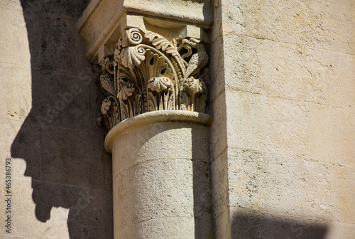 beige stone column head in neo romanesque style. stone textures. fine details od sculpting. religious architecture. faith and religion concept. architectural detail. travel and tourism. photo