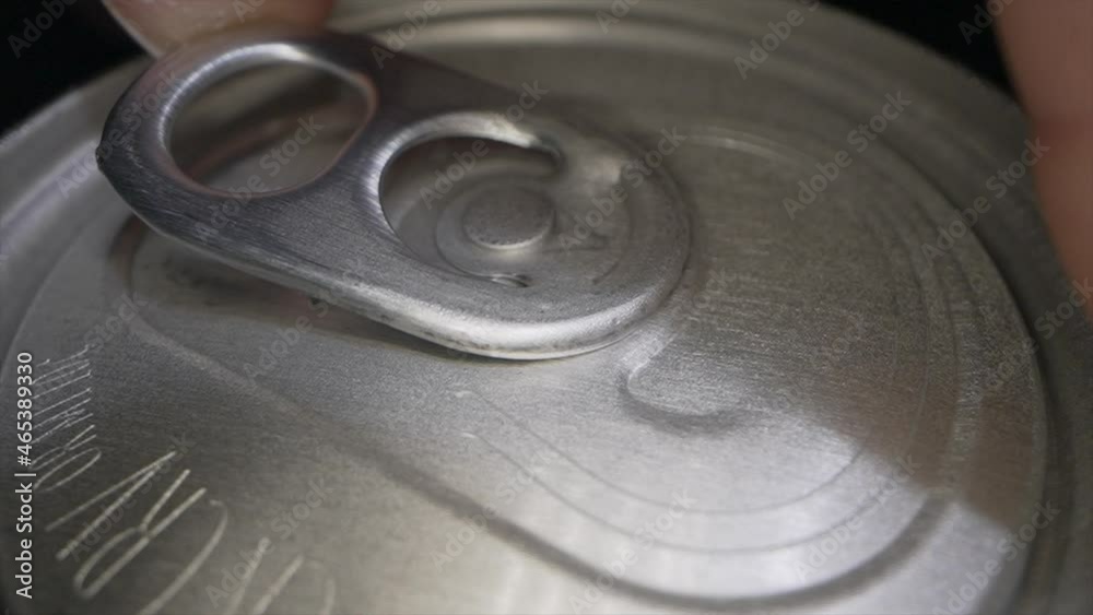 This ultra close up, macro video shows a detailed POV view of a beer can tab opening in slow motion as beer and bubbles explode from the can.
