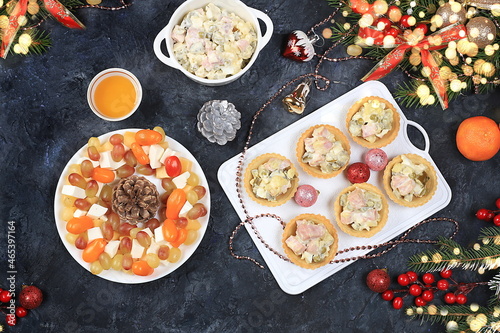 Christmas new year dishes, traditional festive salad olivier and cheese with tomatoes, grapes and honey with fir branches and cones and decorations, dish design idea, photo