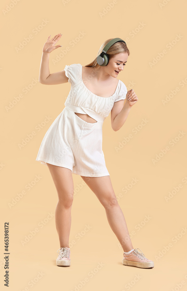 Young blonde woman in headphones singing on beige background Young blonde woman in headphones singing on beige background