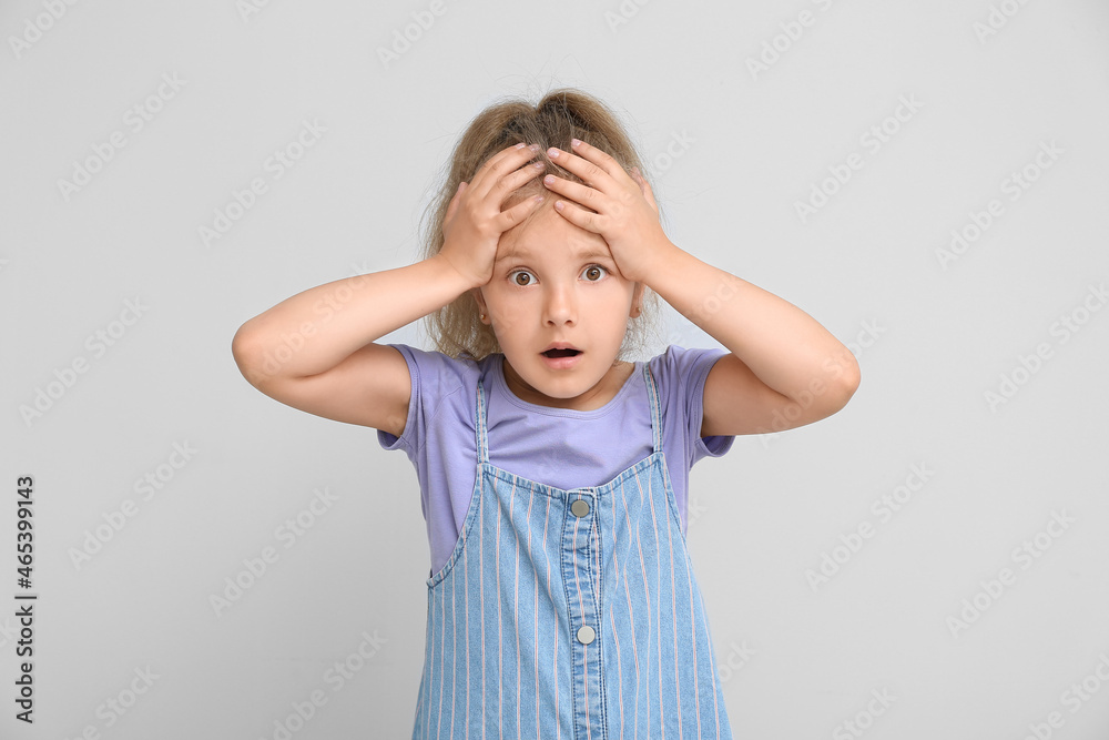 Shocked little girl on light background
