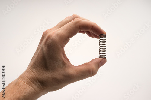 The person's hand grips a silvery metal spring.