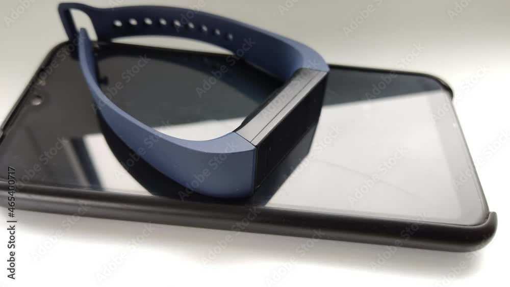 A person puts and picks up a smartphone and a fitness watch on a white table A person puts and picks up a smartphone and a fitness watch on a white table