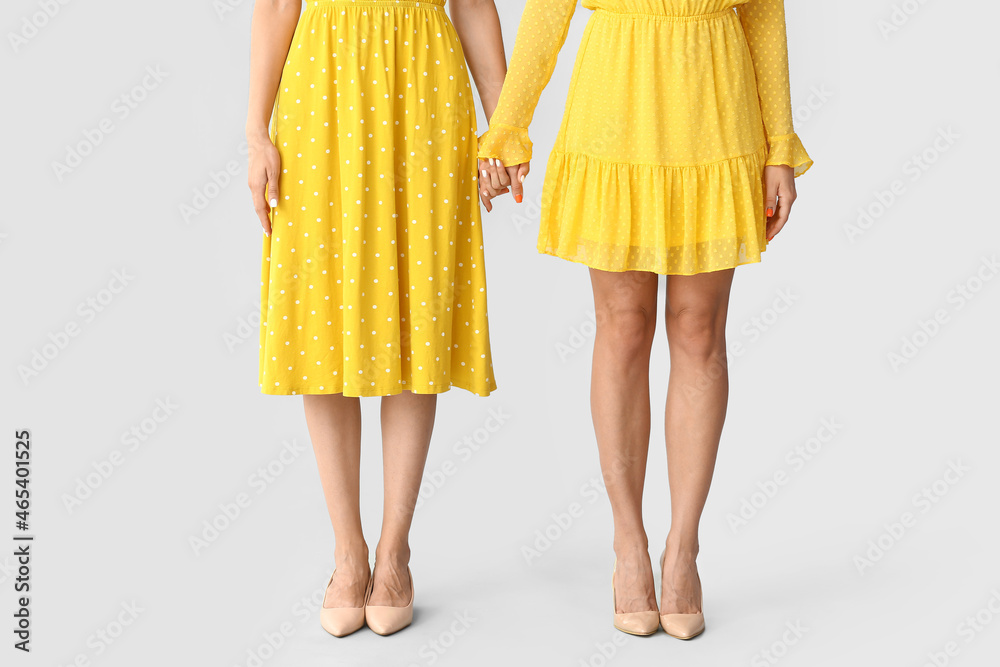Young sisters holding hands on grey background Young sisters holding hands on grey background