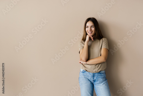 Portrait of a lovely casual girl looking away over beige background