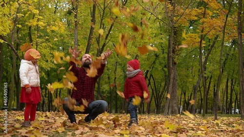 Two happy funny family daddy children kids have fun in park with dad father enjoying autumn fall nature weather. Kid Collect throw up leaves in baskets spend time together playing on forest landscape