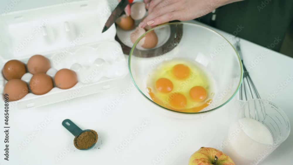 Girl breaks an egg with a knife, Making Apple Pie Girl breaks an egg with a knife, Making Apple Pie
