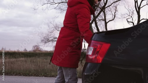 A woman takes a fire extinguisher out of the trunk of a car.