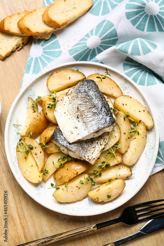 Plate of tasty sea bass fish with potatoes on wooden background