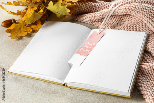 Blank open book with bookmark and oak leaves on light background photo