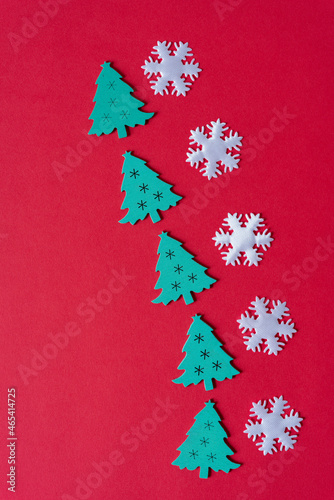 flat wooden christmas tree shapes arranged on a red paper background © eugen